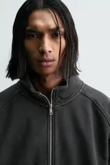 Sudadera de algodón con interior en rizo afelpado, cuello subido, manga larga y cierre frontal de cremallera. Presenta un efecto lavado que le da una apariencia única y bolsillos frontales ocultos en las costuras.