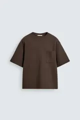 Remera de corte relajado confeccionada en tejido compacto de mezcla de algodón con elasticidad. Presenta cuello redondo, manga corta y un bolsillo frontal de plastrón.
