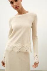 Falda midi de tejido rústico en color beige, con tiro medio, cintura elástica y detalle de aplicación de crochet en el bajo.