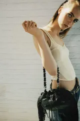 Top corsetero de color marfil confeccionado en tejido elástico, con escote redondo, tirantes anchos y costuras marcadas que estructuran la prenda.