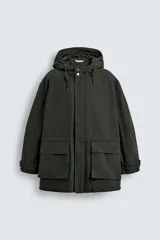 Parka color verde militar de corte relaxed fit, confeccionada en tejido de algodón con interior acolchado. Cuenta con cuello subido, capucha ajustable con cordón, cierre frontal de cremallera oculta por solapa con botones a presión y amplios bolsillos frontales de plastrón con solapa.