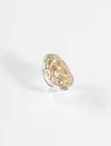 Anillo bicolor de diseño ovalado con superficie texturizada irregular, combinando tonos plateado y dorado.