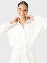Buzo estilo polerón color blanco off-white, confeccionado en tela suave y ligera. Presenta cuello alto, cierre frontal con tapeta de botones a presión, bolsillos frontales con solapa y pretina elástica en la cintura.