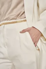 Pantalón de vestir color blanco, de corte recto, con bolsillos laterales y traseros. Se ajusta a la cintura con cinturón de cadena dorada.