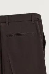 Pantalón de traje flare fit para hombre, confeccionado en tejido con lana, en color marrón oscuro. Presenta tiro medio, trabillas para cinturón, cierre frontal con cremallera y botón, bolsillos laterales y raya central marcada en las perneras.