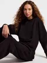 Buzo de cuello redondo en color beige, con diseño liso, mangas largas y puños y ruedo acanalados.