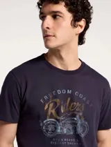 Camiseta blanca de algodón con cuello redondo y mangas cortas. Estampa rectangular con borde negro que contiene la frase "NATURAL ATMOSPHERE" en letras mayúsculas y una imagen de montañas y mar.