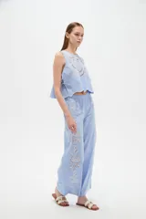 Musculosa de algodón color celeste, con cuello redondo y detalles bordados en tono blanco con diseño de broderie en la parte frontal. Cuenta con cordones laterales para ajustar.