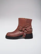 Bota corta de cuero color marrón, con punta cuadrada, suela track negra y estribo desmontable con hebilla metálica.