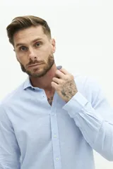 Camisa de manga larga color beige claro, confeccionada en una mezcla de lino y algodón. Presenta un corte semi slim, cuello camisero y un pequeño logo bordado en el pecho.