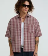 Camisa de manga corta con cuello inglés, corte oversized y estampado de cuadros en tonos rojo, blanco y negro.