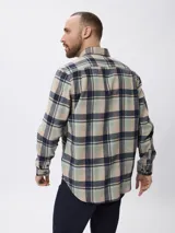 Camisa de manga larga confeccionada en tela de franela con estampado de cuadros en tonos beige, verde y azul marino. Presenta cuello clásico, cierre frontal con botones y un bolsillo en el pecho.