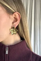 Aros de metal dorado con diseño de flor de cinco pétalos con textura irregular y acabado brillante.