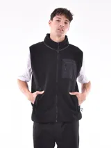 Chaleco negro de tejido polar o sherpa, con cuello alto y cierre frontal. Posee un bolsillo superior en el pecho con cierre y bolsillos laterales con cierre.