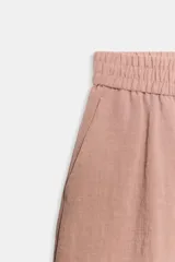 Bermuda de tiro alto de lino color rosado, con cintura elástica trasera, bolsillos delanteros, bajo con vuelta y cierre frontal con cremallera y botones.