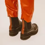 Botas negras de cuero estilo chelsea, con suela track gruesa y elásticos laterales. Presentan una tira vertical de cuero marrón en la parte posterior.