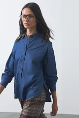 Camisa de jean en tencel de silueta amplia, con hombros caídos, mangas largas, cartera frontal con botones, ruedo curvo con tajos laterales y pliegue en la espalda.