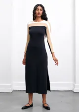 Vestido midi negro con bloques de color blanco y beige en la parte superior, de corte recto y mangas largas.