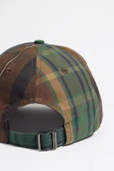Gorra de béisbol con diseño patchwork de cuadros en tonos marrones, verdes y azules. Presenta el logo de la marca bordado en el frente y visera curva.