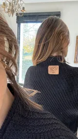 Poncho tejido en lana merino color marrón, con diseño de punto acanalado y terminación con flecos en el borde inferior. Incluye una pequeña etiqueta de cuero en la parte posterior.