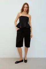 Top negro strapless con escote recto y bajo acabado en peplum. Cuenta con cierre lateral con cremallera oculta en costura.