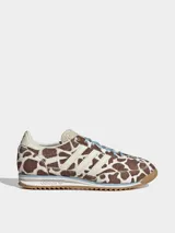 Championes Adidas modelo SL 72 OG con diseño de perfil bajo. Presentan una parte superior de piel con acabado de pelo de poni con estampado animal print de manchas marrones y blancas. Incluyen las icónicas tres tiras laterales en color crema, cordones celestes y suela de goma con entresuela de EVA.