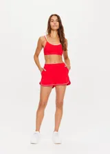 Short deportivo rojo con ribetes blancos, de tiro medio, con bolsillos frontales y bolsillo trasero.
