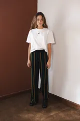 Pantalón negro con rayas verticales en amarillo, verde y rojo. Tejido con elástico en la cintura y lurex.