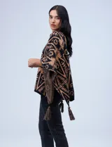 Poncho tejido con diseño tribal en blanco y negro, terminación con borlas.