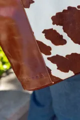 Bolso tote de cuero marrón con panel central de cuero con estampado animal print de vaca.