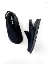 Zuecos negros de cuero con tira trasera y hebilla ajustable.