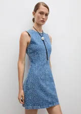 Vestido corto de denim con efecto desgastado, sin mangas y cuello redondo. Presenta un diseño entallado con costuras decorativas verticales y cierre de cremallera en la parte posterior.