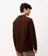 Remera de manga larga color marrón, confeccionada en tejido texturizado con cuello en V tipo polo. Presenta un diseño de calce confortable y acabado moderno.