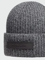 Gorro tipo beanie de punto mouliné en tonos grises, con parche de logo Moncler en la parte frontal.
