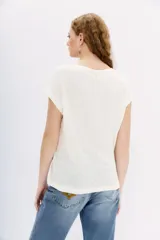 Remera negra de lino con moldería holgada y mangas cortas. Presenta pequeños apliques de strass distribuidos por toda la prenda.