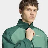 Campera deportiva Adidas Múnich 93 en tonos de verde, con cuello alto, cierre frontal y las icónicas tres tiras en las mangas. Diseño holgado con detalles en contraste.