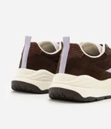 Championes estilo runner de la marca Satinato, confeccionadas en una combinación de poliuretano y mesh respirable. Presentan un diseño con recortes superpuestos en tonos marrón y detalles en lila, cierre con cordones bicolor, lengüeta acolchada, tirador trasero y una suela robusta con entresuela alta y base tractorada.