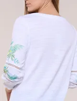 Blusa blanca de silueta semi entallada, confeccionada en tejido texturado. Cuenta con escote en V con abertura y vivo bordado multicolor, mangas 3/4 abullonadas con bordados, calados y puños elásticos.