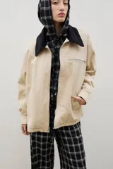 Campera de gabardina color beige con cuello de pana negro, cierre frontal metálico, bolsillos laterales y bolsillo superior con cierre.