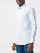 Camisa Tommy Hilfiger de algodón Oxford celeste con microestampado. Tiene corte regular, cuello abotonado, mangas largas con puños abotonados y logo bordado en el pecho.