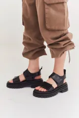 Sandalias marrones con tiras de cuero con ajuste de velcro y detalles en amarillo.