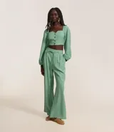 Pantalón wide leg color verde agua, de tiro alto y corte sastrero, con cintura elástica en la espalda, cinturón incorporado para lazo, pliegues delanteros y bolsillos laterales.