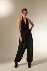Pantalón tipo babucha de color negro, confeccionado en tela semitransparente con textura de rayas verticales y pequeños detalles en relieve. Presenta una cintura elástica cómoda y un corte holgado que se ajusta ligeramente en los tobillos.
