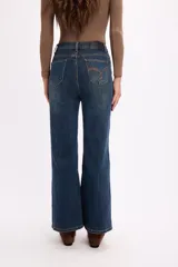 Jean de corte flare con tiro alto, confeccionado en denim azul con costuras laterales marcadas y ruedo desflecado.