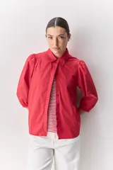 Camisa blanca de algodón, de calce relajado, con cuello camisero, frente abotonado y mangas largas abullonadas.