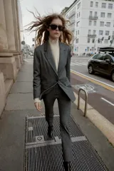 Leggings de tiro alto color gris oscuro, con cintura elástica, falsos bolsillos de vivo en la espalda y pernera larga acabada en evasé. Cierre frontal con cremallera, botón interior y gancho.