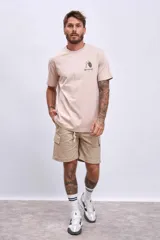 Remera de hombre color beige con estampado frontal de un llavero con la frase "Early Check Out".