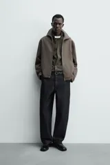 Sobrecamisa relaxed fit de Zara confeccionada en tejido negro con estructura diagonal. Presenta cuello subido, manga larga, bolsillos de vivo en la cadera y cierre frontal con cremallera.