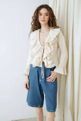Blusa de voile color beige, de manga larga, con volados en el escote en V y tirantes frontales para atar.