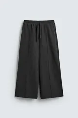 Pantalón de corte wide fit en tejido con acabado cepillado, color gris oscuro. Presenta cintura elástica con cordón ajustable, bolsillos delanteros y bolsillos traseros de plastrón.